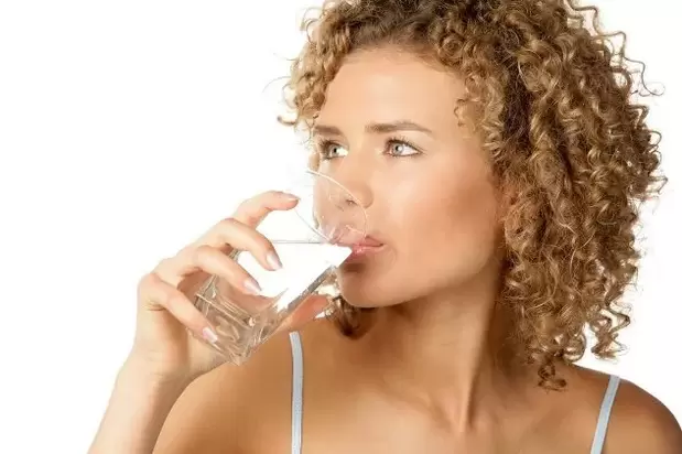 A rapaza fai unha dieta preguiceira e bebe un vaso de auga antes de comer